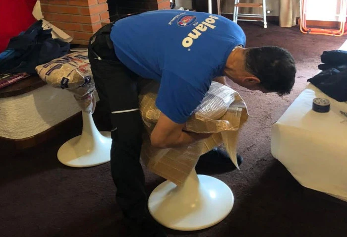 Un operatore imballa uno sgabello durante il trasloco